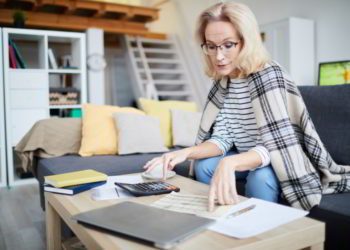 Portrait of contemporary mature woman calculating taxes