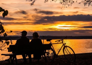 Couple sitting together on a bench watching the sunset, while enjoying the benefits of the Belize QRP Program.