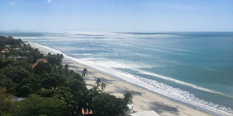 Blue skies and white and black sand beach in Coronado, Panama