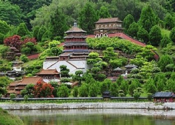 A hillside with a temple in China with water in front and