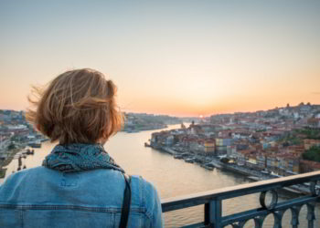 Redhead woman observing the sunset in Porto, Portugal on the bridge over the river