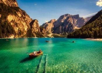 Rowing boats on a clear lake in Italy. Rocky mountains border the lake