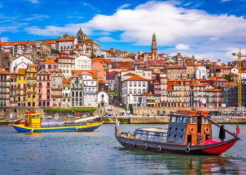 View of Porto Portugal, two colorful boats with the city behind them. taxes in portugal