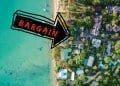 An aerial view down at homes along the beach with an arrow pointing to bargain properties. Buying cheap real estate overseas