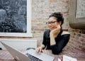 a teacher on her laptop with blackboard in background