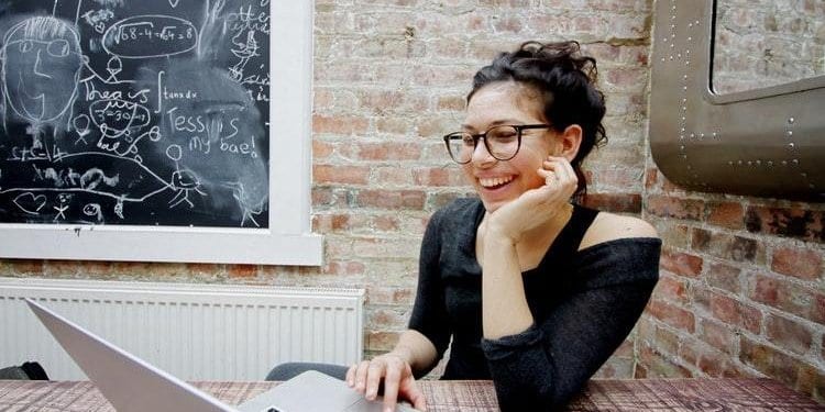 a teacher on her laptop with blackboard in background