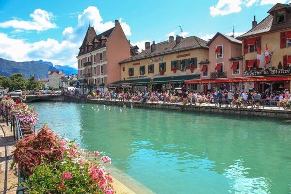 Blick über den Kanal auf Menschen, die Essen und Trinken im Freien in Annecy, Frankreich genießen