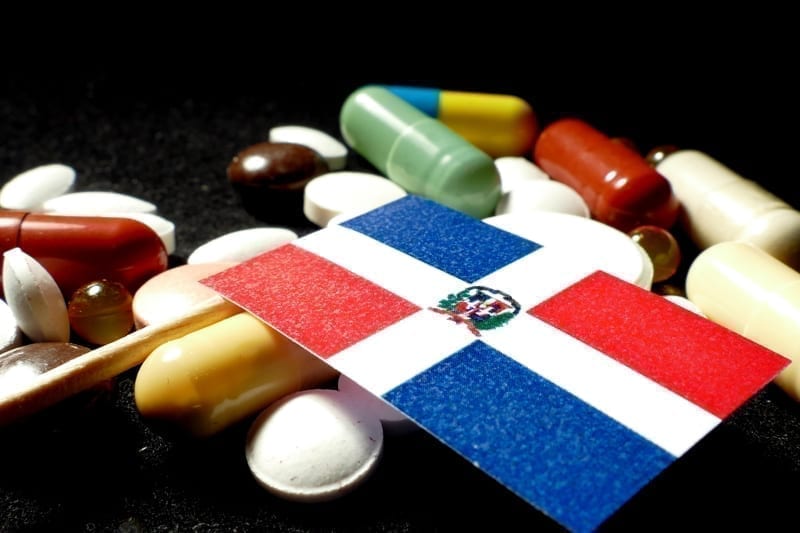 Dominican Republic flag with lot of medical pills on black background