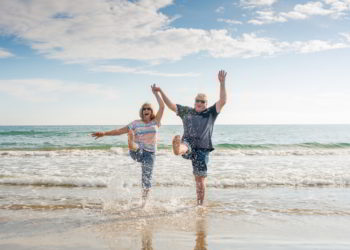 Senior couple walking on the beach having fun in a sunny day