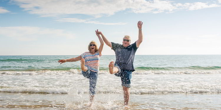 Senior couple walking on the beach having fun in a sunny day