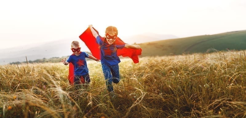 Happy children boy and girl in costumes of superheroes in the outdoor.