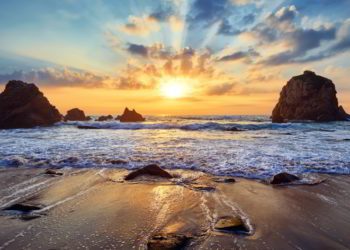 Sand beach among rocks during sunset in Portugal.