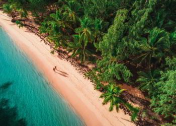 Two people walking on a white sand beach in Dominican Republic. Snowbird Destination