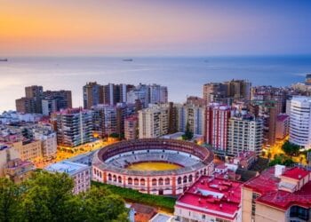 Malaga, Spain at dawn with colorful buildings and the sea in the background.