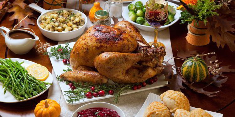 Rustic Thanksgiving dinner with turkey, cranberry sauce, stuffing, green beans, biscuits, gravy, Brussel sprouts, and wine