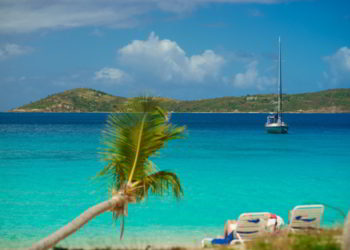 Relaxing on chair on the beach with palm and yacht on background