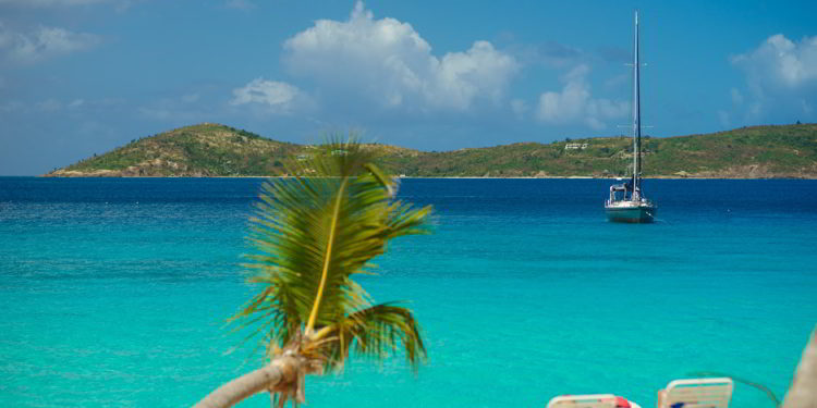 Relaxing on chair on the beach with palm and yacht on background