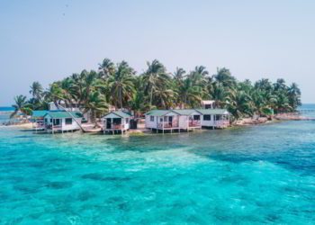 View of Tobacco Caye small Caribbean island with palm trees and bungalows in the Belize Barrier Reef