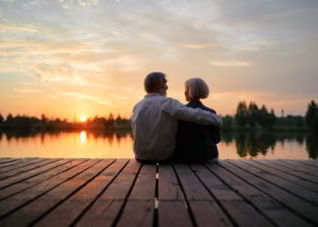 Senior couple sitting together on lake bank