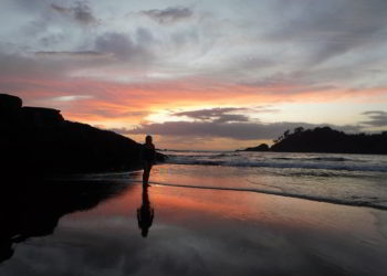 A person standing on a beach during sunset in Los Islotes, Panama