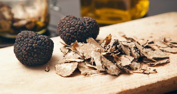 Two truffles and truffle shavings on a cutting board