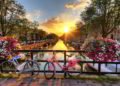 Beautiful sunrise over Amsterdam, The Netherlands, with flowers and bicycles on the bridge in spring