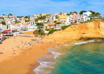 View of beach with in Carvoeiro town with colorful houses on coast of Portugal