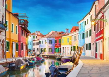 Colorful houses next to a canal with boats in Burano, Venice, Italy