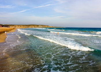 People enjoying the clear blue waters and sandy beach in Bafra, Cyprus