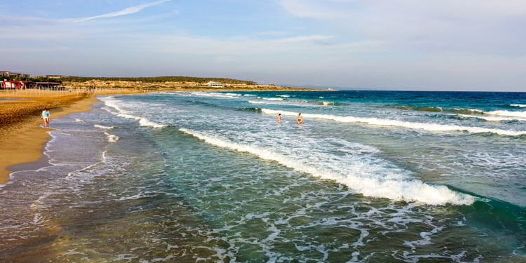 People enjoying the clear blue waters and sandy beach in Bafra, Cyprus