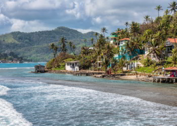 Palm trees, sea and houses in Isla Grande shore. Colon province, Panama 