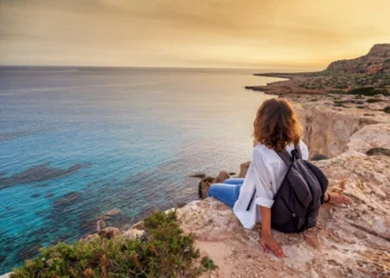 Woman traveler watches a beautiful sunset on the rocks on the beach, Cyprus, Cape Greco