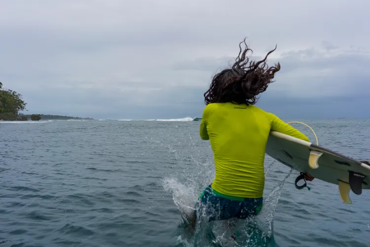 surfer gets in the water, bocas del toro, panama city beaches area