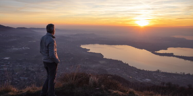 Hiker looking sun over horizon