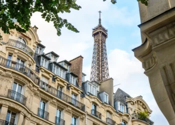 Top of the Eiffel Tower seen from down the street with foliage and typical residential buildings in the foreground. asset protection