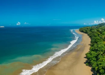 Aerial Drone View of a tropical beach in Costa Rica. Sand and water surrounded by lush rainforest