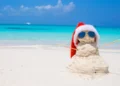 Sandy snowman with red Santa Hat on white Caribbean beach. Legend Among Travelers