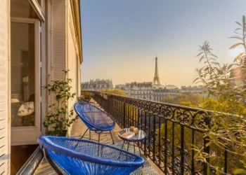 Blue chairs in a Paris balcony at sunset with the Eiffel Tower in the background, France