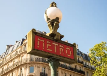 A traditional Paris Metro sign with buildings in the background. Europe Cities