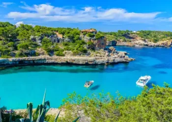 Summer vacation scene with sailboats on turquoise clean water on Mallorca Island near Cala Llombards beach.