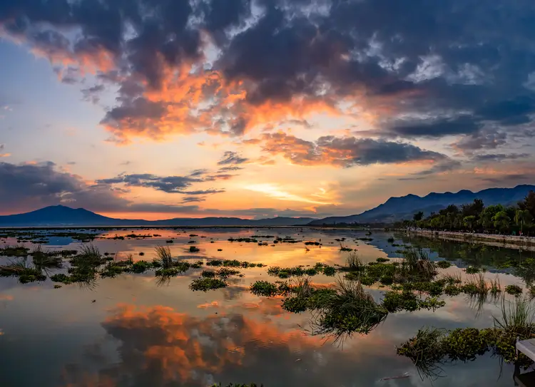 Orange and red sunset with misty mountains behind lake Chapala and the malecon on the right. mexico ajijic