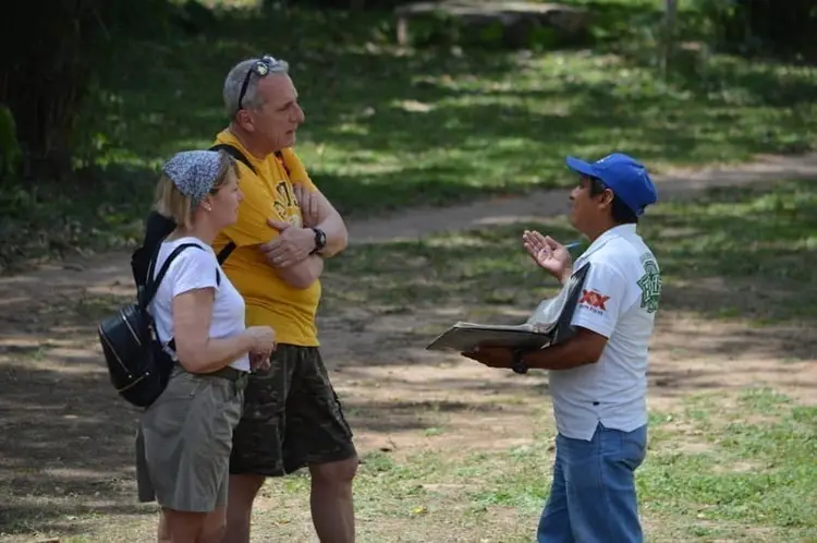 A tour guide with two tourists at the Acropolis pyramid at Ek Balam ruins, Mexico