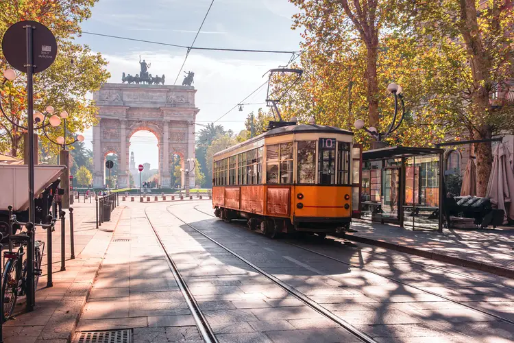 Famous vintage tram in the centre of the Old Town of Milan in the sunny day, Lombardia, Italy. Arch of Peace, or Arco della Pace on the background. travel in italy