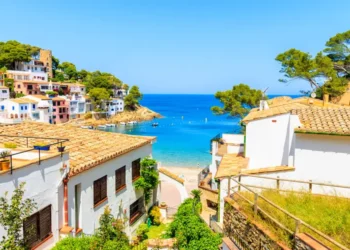 White houses with orange tile roofs and steps to beach in Sa Tuna coastal fishing village, Costa Brava, Spain