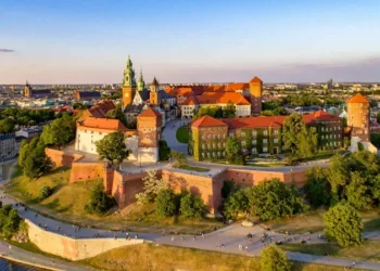 Poland. Krakow skyline with Wawel Hill, Cathedral, Royal Wawel Castle, defensive walls,Vistula riverbank, park, promenade, walking people.