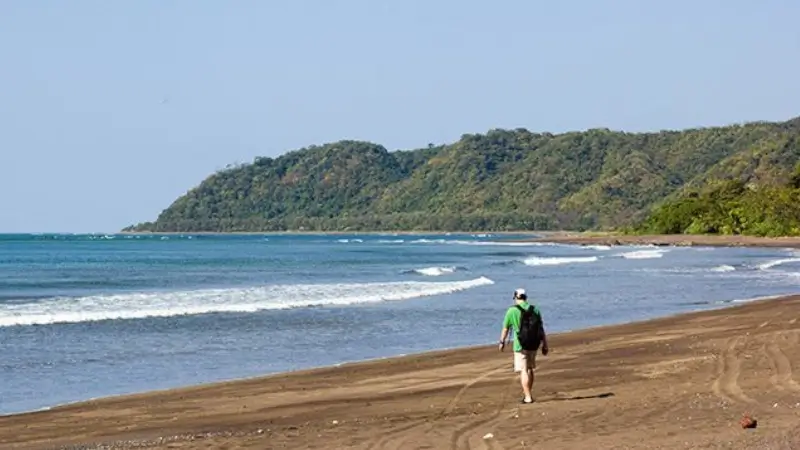 a man wearing a backpack walking on an isolated beach