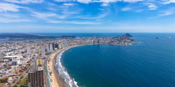 An aerial view of Mazatlán Beach on a sunny morning, showcasing the blue ocean's gentle waves meeting the sandy shores of this popular tourist destination