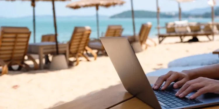 Closeup of a woman working and typing on laptop computer on the beach