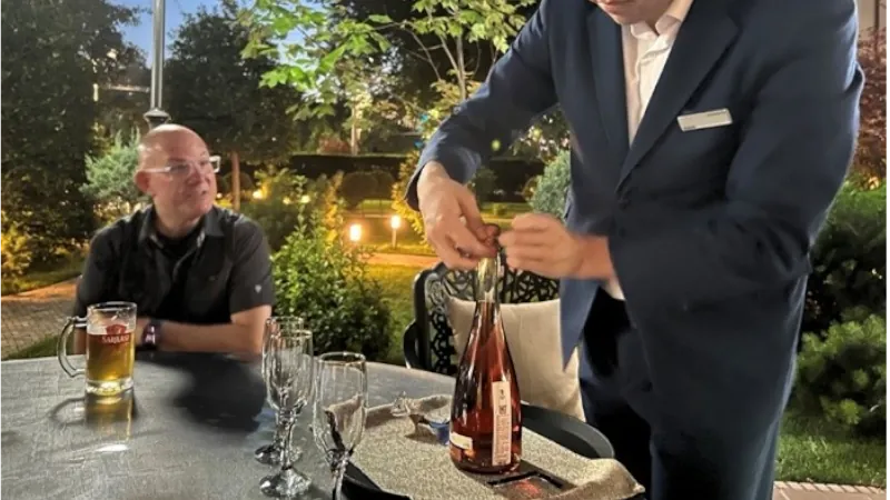 A local Server Opens A bottle of pink bubbly at Tashkent Uzbekistan