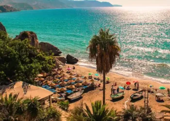 Nerja, Málaga. Sunny view of the Mediterranean Sea from Costa del Sol. With clean water, people at the sand and giant palm trees.